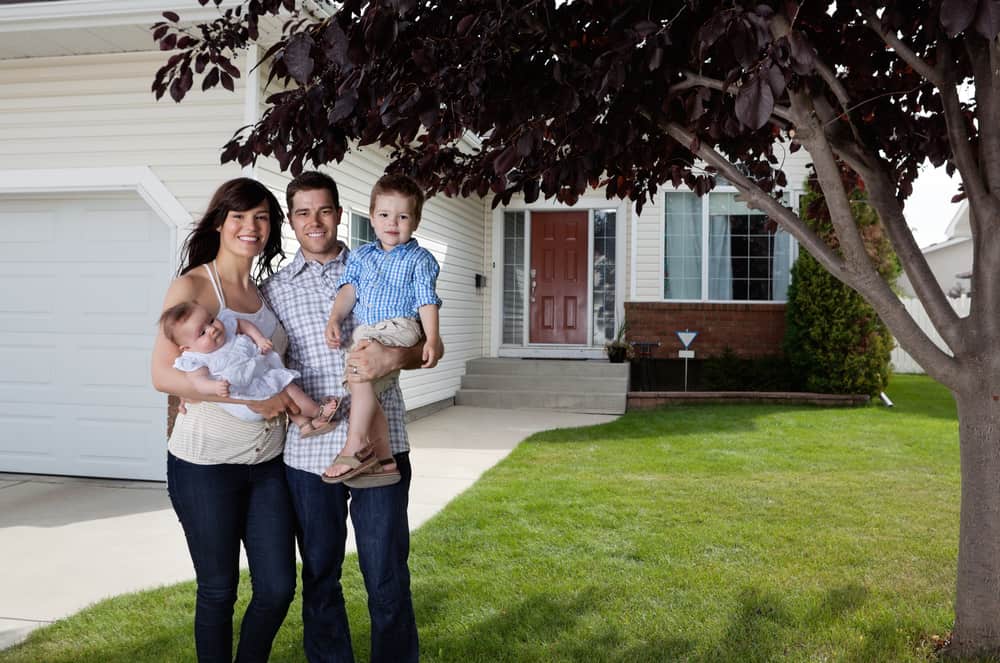 Portrait d'un couple heureux debout avec leurs enfants devant une maison